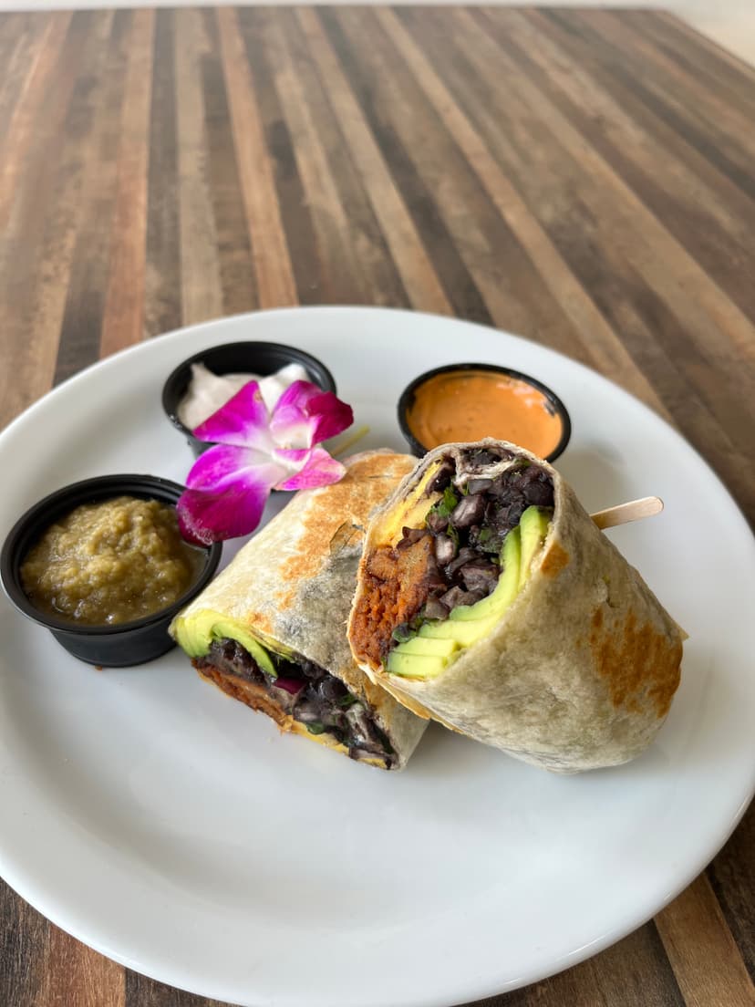 Vegan al pastor burrito, halved, with salsas on the side